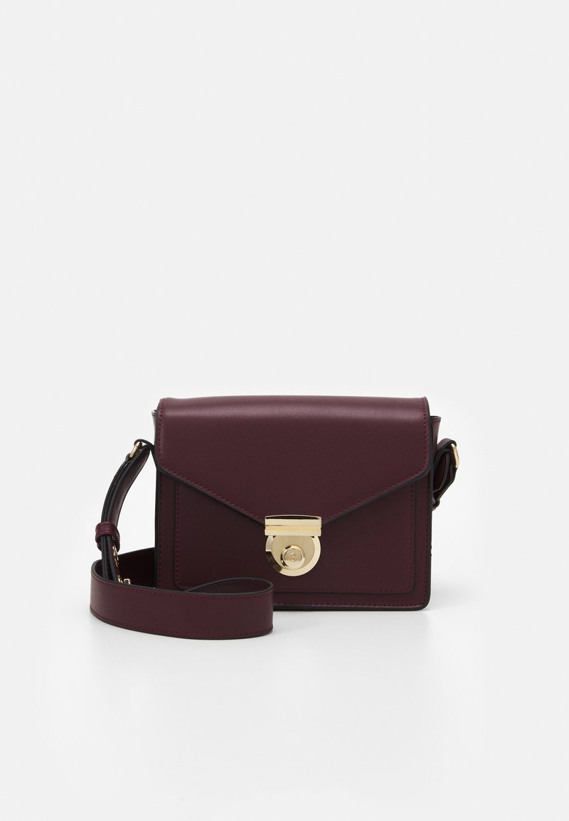 Borsa a tracolla in pelle bordeaux con una chiusura circolare dorata, caratterizzata da un design strutturato, tracolla regolabile e accenti minimalisti.