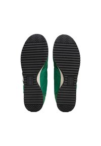 Zapatillas verdes con una suela de goma negra texturizada. Presentan un empeine suave con acentos en blanco contrastantes y un logo en el costado.