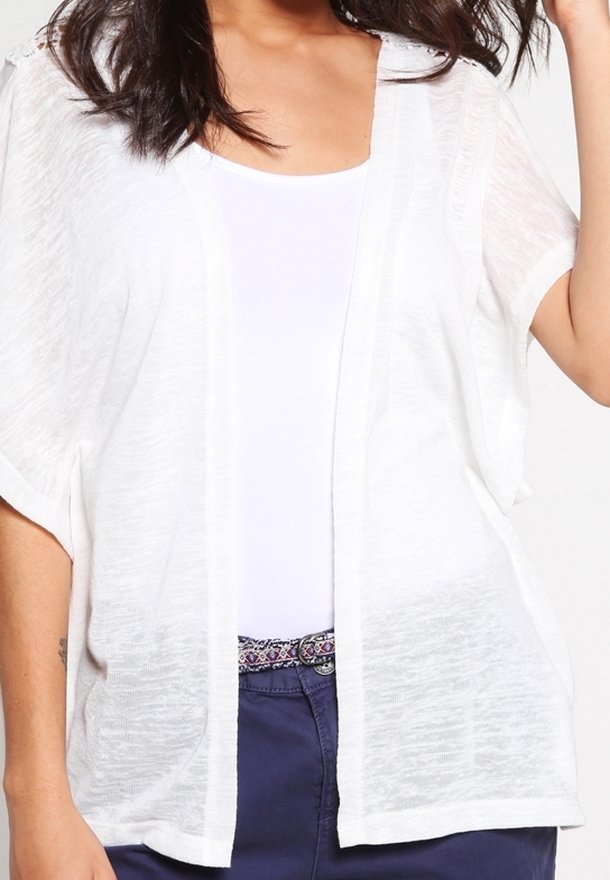 Bílý lehký kimono-styl kardigan s otevřeným předním dílem, krátkými rukávy a jemnou texturou, přeložený přes jednoduchý bílý top a tmavé kalhoty.