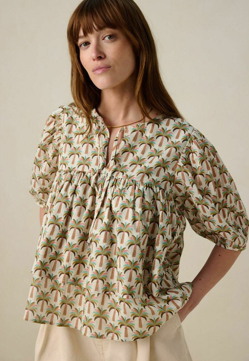 Korte mouwen blouse in crème met een palmboomprint. Heeft een ronde hals, een geraffineerde taille en zachte, lichte stof.