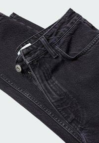 Jean en denim noir plié montrant la poche avant, les passants de ceinture, le bouton et les détails de la fermeture éclair sur fond blanc.
