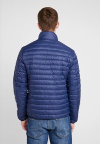 Marineblaues Daunenjacke mit horizontalem Steppmuster, hohem Kragen und leichtem Material. Texturierte Oberfläche mit elastischen Bündchen.