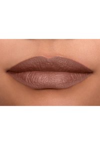 Matte läppstift i en neutral brun nyans, med en jämn textur och subtila linjer. Läpparna är fylliga, med en definierad form och en naturlig finish.