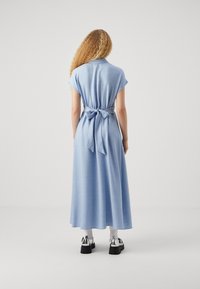 Abito maxi azzurro chiaro con maniche corte, vita legata, tessuto fluido e design semplice e senza decorazioni.