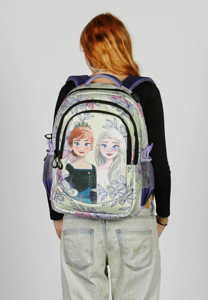 Mochila con una tela suave que presenta diseños gráficos de dos personajes, rodeados de patrones florales en colores pastel y un bolsillo con cremallera.