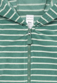 Grøn fleece zip-up heldragt med hvide vandrette striber, med hætte og plastik lynlås. Etiketten læser "Carter's" og størrelse "6 måneder."