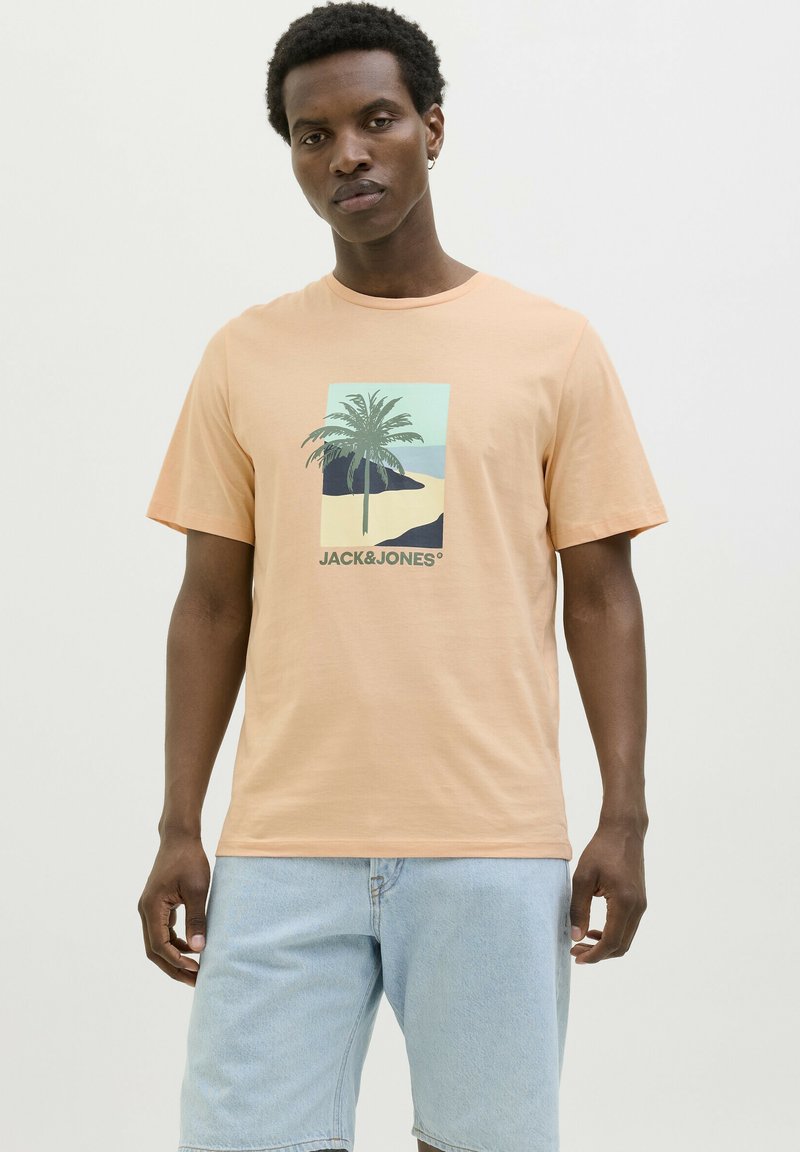 Camiseta de manga corta en color durazno claro con un gráfico de palmera y el texto "JACK & JONES" en la parte inferior. Corte clásico, hecha de material de algodón.