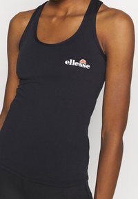 Schwarzes, figurbetontes Tanktop aus dehnbarem Material. Verfügt über einen runden Ausschnitt und ein weißes Logo-Detail auf der Brust. Einfaches, schnörkelloses Design.