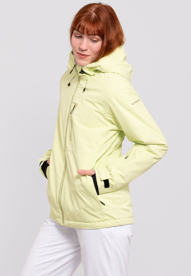 Hellgelbe isolierte Jacke mit Kapuze, ausgestattet mit schwarzen Akzenten, Reißverschlusstaschen und verstellbaren Kordeln für eine sichere Passform.
