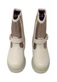 Stivaletti beige alla caviglia con punta in pelle liscia, pannelli laterali in rete metallica e chiusura con zip. Presentano una fascia con un accentuato fibbia dorata.