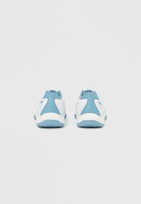 Ζεύγος λευκών και γαλάζιων αθλητικών παπουτσιών, ορατά από πίσω, σε απλό λευκό φόντο.