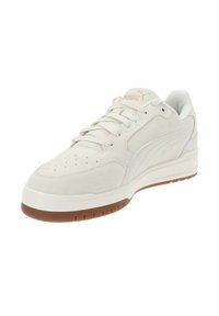 Zapatilla de ante blanca con puntera redondeada, diseño de cordones, parte superior perforada para transpirabilidad y suela de goma. Acento de logo dorado en la lengüeta.