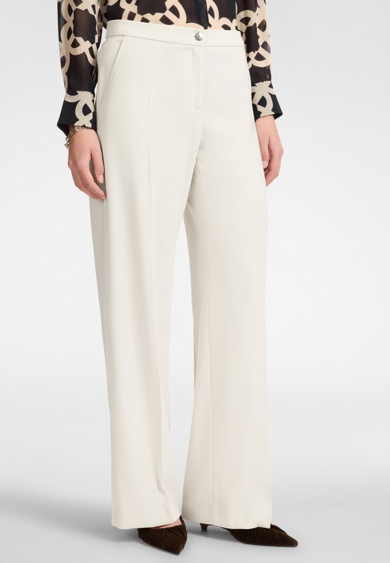 Pantalones de pierna ancha en tejido blanco con textura suave, que presentan un cierre frontal con un botón plateado y bolsillos.