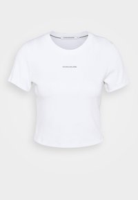 White cotton cropped t-shirt with short sleeves, crew neck, and "CALVIN KLEIN JEANS" logo in black centered on the chest. Smooth texture.