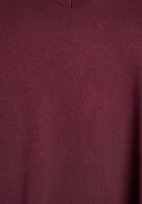 Pull en V bordeaux en tissu doux et texturé ; présente une coupe classique avec une finition lisse et sans motifs ni accents visibles.