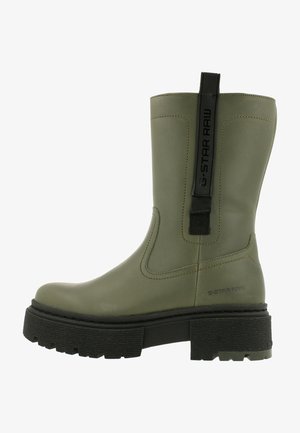 Groene rubberen enkellaarsjes met een gestructureerde zwarte zool, voorzien van een trekhaak en het G-Star Raw-logo aan de zijkant. Glad, waterdicht materiaal.