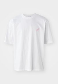 T-shirt bianco in cotone a maniche corte, con un piccolo logo rosa e tre stelle sulla parte sinistra del petto. Design semplice e a vestibilità rilassata.