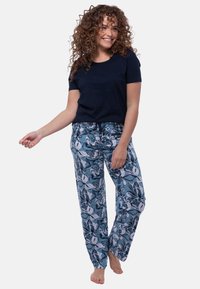 Laivastonsininen puuvillapaita yhdistettyinä löysiin, sinivalkoisiin kukkakuosisiiin pyjamahousuihin, joissa on säädettävä naru vyötäröllä.