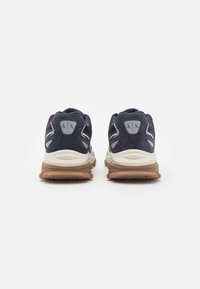 Baskets de sport en daim et mesh bleu marine avec une semelle intermédiaire crème et une semelle extérieure marron, avec un logo au niveau du talon et un dos rembourré.