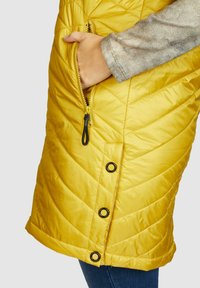 Gequilte gele puffer vest met een ritszak, zwarte hardware accenten en een ronde zoom, met een gladde, glanzende textuur.