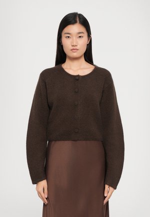 Brown knitted cardigan with long sleeves, featuring a round neckline and five button closures, worn over a brown dress.