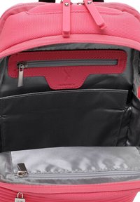 Interno dello zaino rosa con una tasca texturizzata, fodera grigia, una compartimento con cerniera e diverse sezioni organizzative.