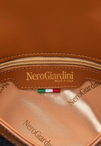 Interno in pelle tan con tasca con zip. Caratterizzato dal logo dorato "NeroGiardini MADE IN ITALY" e una piccola bandiera italiana. Texture liscia.