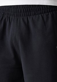 Pantaloni sportivi neri in tessuto testurizzato, con una vita elastica e un piccolo logo sul lato.