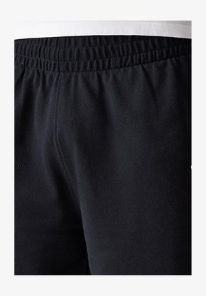 Shorts de sport noirs en tissu texturé, avec une ceinture élastique et un petit logo sur le côté.