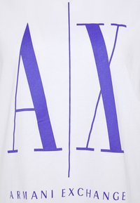 Biała bawełniana koszulka z dużym fioletowym logo "AX" i napisem "ARMANI EXCHANGE" poniżej, wyśrodkowanym i w grubym kroju pisma.