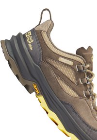 Chaussure de randonnée marron et grise avec une tige texturée, des panneaux en maille et une semelle épaisse Vibram avec des accents jaunes. Marque Texapore visible.