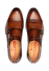 Bruine leren schoenen met een gladde afwerking, voorzien van twee gespen en een afgeronde neus. Binnenin bevindt zich een beige inlegzool met rode "Pikolinos" branding.