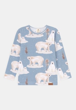Blå skjorte med lange ærmer med gentagne illustrationer af isbjørne, der står og sidder på isflager med små træer i en snedækket scene.