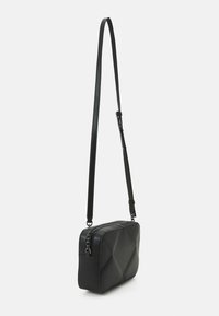 Borsa a tracolla rettangolare nera in pelle liscia con design trapuntato, dotata di una lunga cintura regolabile e chiusura con zip superiore.