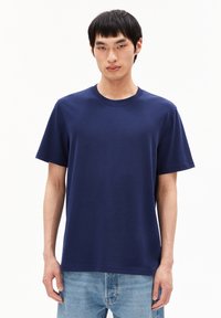 Navyblauwe katoenen t-shirt met korte mouwen en een ronde hals. Soepel textuur en een losse pasvorm, gecombineerd met lichtblauwe jeans.