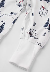 Langärmliges Kleidungsstück mit weißem Grund und bunten Mumin-Figuren sowie Bäumen. Weicher Stoff mit elastischen Bündchen und Reißverschluss.