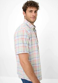 Camicia a maniche corte in plaid dai colori pastello, con colletto button-down e tessuto leggero. I motivi includono linee incrociate in diverse sfumature.