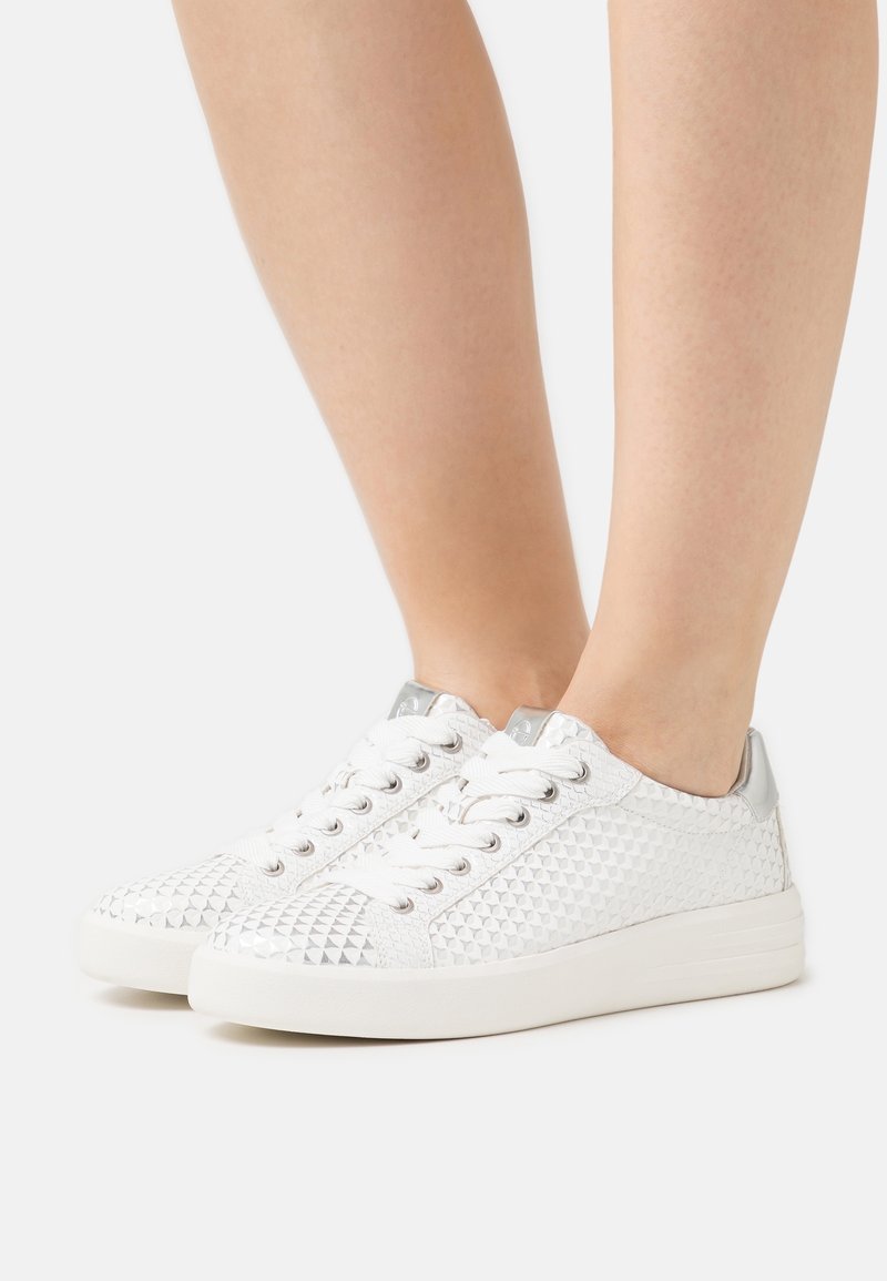 Baskets blanches avec motif en diamant texturé, accents argentés et lacets blancs. Dotées d'une semelle blanche lisse et d'un design à bout arrondi.