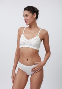 Vitt ribbat bralette med små blommönster, justerbara axelband, tillsammans med matchande vita bikiniunderbyxor med en enkel design.