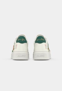 Sneaker bianche ALDO viste da dietro, con tacchetti verdi e scritta dorata, patch decorativi sui lati e suole spesse.