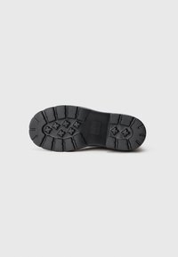 Suela de goma negra con un patrón de banda de rodadura texturizado, que presenta cruces elevados para mayor agarre y una sección central lisa. Bisel plano, diseño duradero.