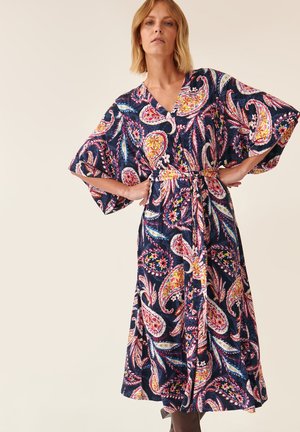 Abito fluido navy con grande motivo paisley in vivaci tonalità di rosa, giallo e verde. Presenta maniche ampie e una cintura in tessuto da legare in vita.