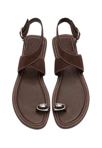 Brązowe zamszowe sandały z krzyżującymi się paskami, z klamrą na kostkę i akcentami w kolorze srebrnym. Płaska podeszwa z detalem w postaci przeszyć. Otwarty design palców.