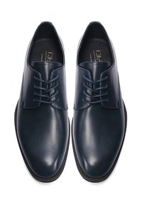 Zapatos de vestir de cuero azul oscuro con una textura suave, punta redonda y diseño de cordones con seis ojales. Plantillas de cuero y suelas de goma delgada.