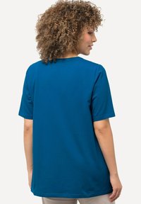 T-shirt blu a maniche corte realizzato in tessuto morbido. Caratterizzato da un collo rotondo e una vestibilità morbida. Sul retro presenta un colore uniforme senza grafiche visibili.