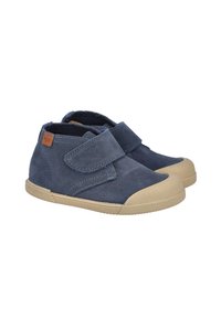 Zapatos para niños pequeños de ante azul marino con suelas y punteras de goma beige, con una sola correa ancha de Velcro y una pequeña etiqueta de marca marrón.