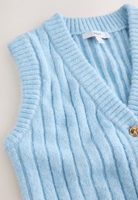 Vestă fără mâneci din tricot cu dungi, de culoare albastru deschis, cu decolteu în V și un mic nasture decorativ auriu lângă guler.