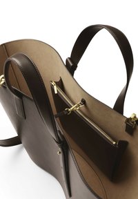 Sac cabas en cuir marron foncé avec double anses, ouverture supérieure, et une pochette intérieure zippée attachée par un fermoir doré.