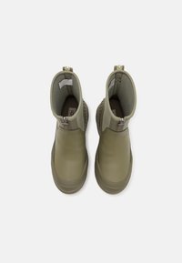 Botas de tobillo color verde oliva con una textura suave, cierre de cremallera y acentos laterales texturizados. Diseñadas para facilitar el calzado y descalzado. Suela de goma plana.