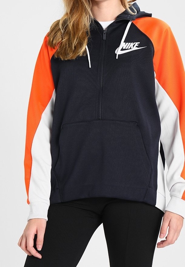 Felpa con zip di colore blu navy e arancione, dotata di tasca a marsupio, dettagli bianchi sulle maniche e logo Nike bianco sul petto. Realizzata in tessuto morbido.
